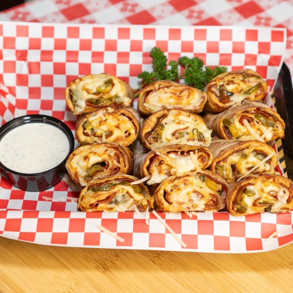 Baked pizza rolls with cheese and jalapeños, served with a side of ranch dressing.