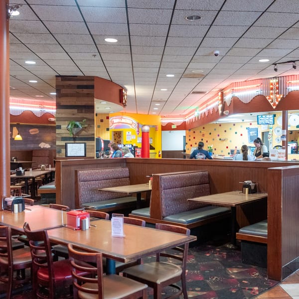 A diner interior with booths, tables, and a counter where staff are serving customers.