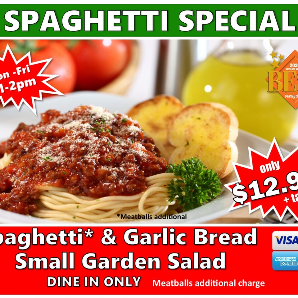 Spaghetti with meat sauce, parmesan, and garlic bread, with tomatoes and olive oil in the background.