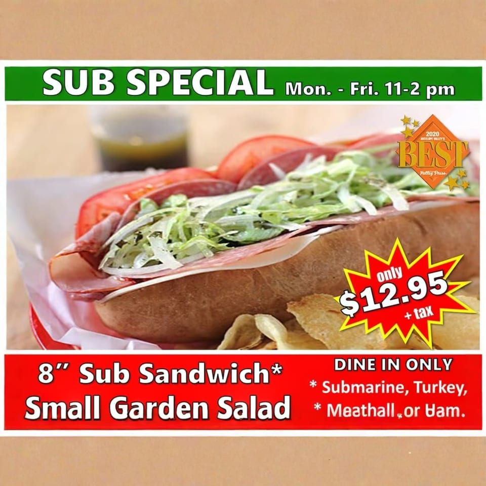 A sub sandwich with lettuce, tomatoes, and deli meat, next to potato chips and a drink.